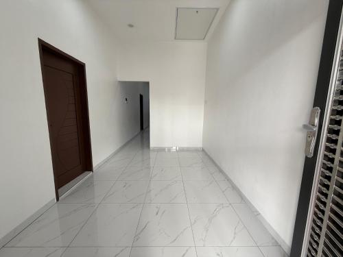 a hallway with a door and white walls and a tile floor at 吉胆岛玖壹壹民宿 in Bagan Teochew