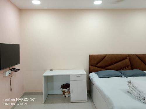a white bedroom with a bed and a tv at Rhino Inn Guest House in Guwahati