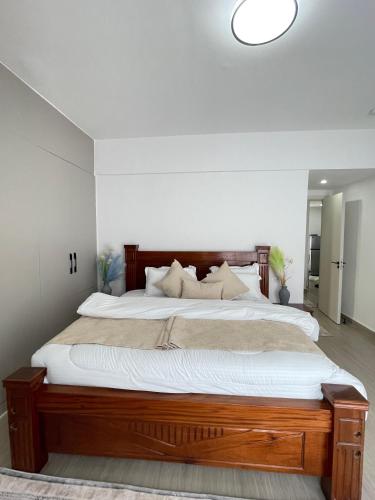 a bedroom with a large wooden bed with white sheets at Furnished 2-Bedroom Apartment with Swimming pool, Gym and Sauna in Gatunga