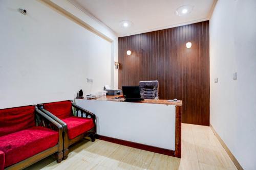 an office with a red couch and a desk with a laptop at Maayra Inn in Noida