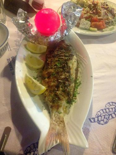 a white plate with a fish and some lemon slices at Limnionas Bay Village Hotel in Marathokampos
