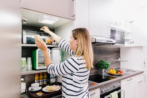 een vrouw in een keuken die eten in een broodroosteroven doet bij Business and Family Homes in Burgau