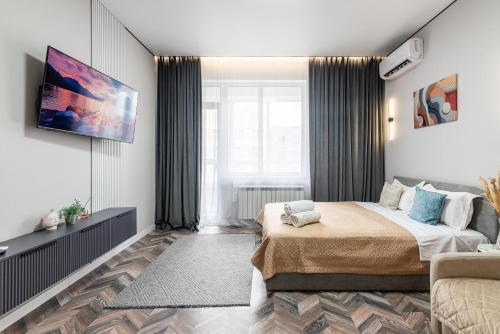 a bedroom with a bed and a tv on a wall at Квартира в стиле лофт in Almaty