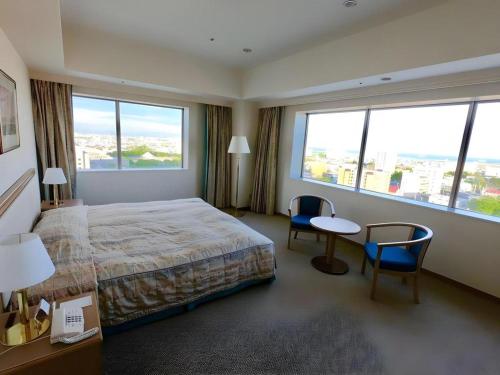 a hotel room with a bed and a table and chairs at Grand Hotel New Oji in Tomakomai