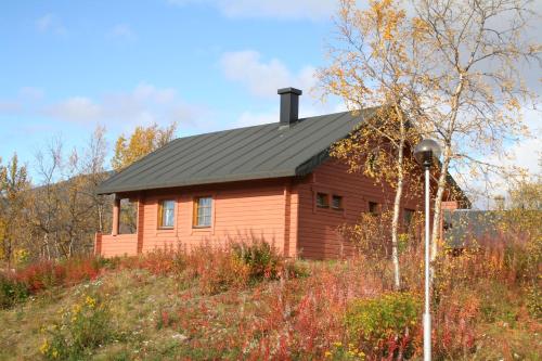 a house with a black roof on top of a hill at Tundrea Holiday Resort in Kilpisjärvi