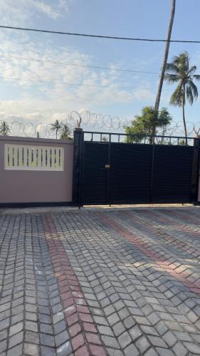 a black gate with a fence and palm trees at Abode of peace Airport stay in Dar es Salaam