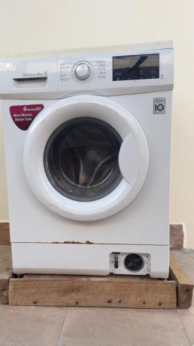 a white washing machine sitting on a wooden platform at Abode of peace Airport stay in Dar es Salaam
