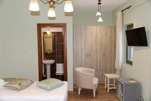 a bedroom with a bed and a chair and a sink at Alexandra Hotel in Kalentzi