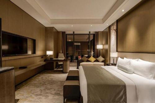 a hotel room with a large bed and a television at Golden Eagle Summit Hotel Kunshan in Suzhou