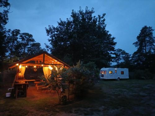 a tent and a table and a trailer in a field at Wood Camping in Brochów