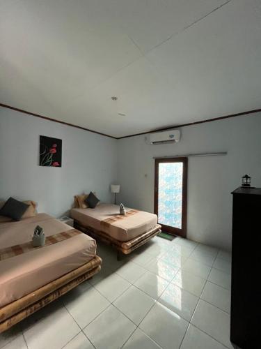 two beds in a room with a window at Kebun Homestay in Kuta Lombok