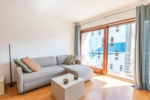 a living room with a couch and a large window at Cosy condo in the city centre in Ostend