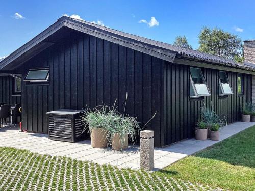 a black building with potted plants in front of it at 6 person holiday home in Hals in Hals