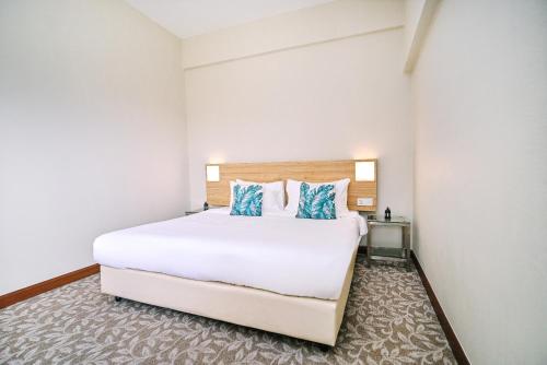 a bedroom with a large white bed with blue pillows at Kingston Hotel 10 - Bukit Jalil in Serdang