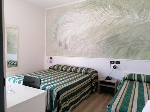 a bedroom with two beds and a painting on the wall at Hotel Villa Maria in Caorle