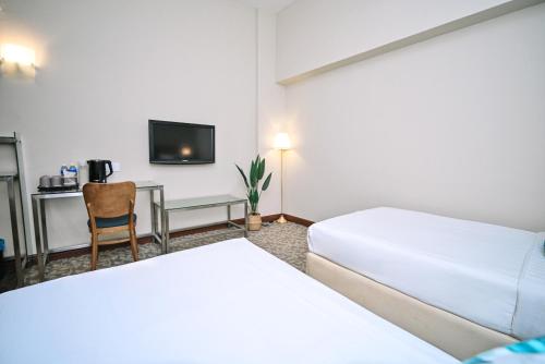 a hotel room with two beds and a desk at Kingston Hotel 10 - Bukit Jalil in Serdang