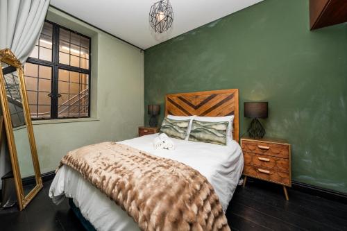 een slaapkamer met een bed en een groene muur bij Stylish City Gem Apartment in Green Market Square in Kaapstad