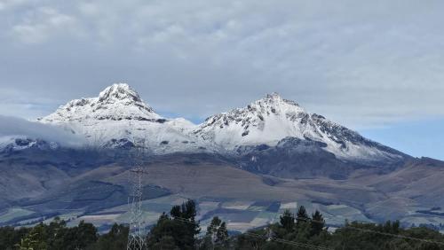 a snow covered mountain in the distance with trees in front at Häuschen nahe Cotopaxi-House near Cotopaxi in Machachi