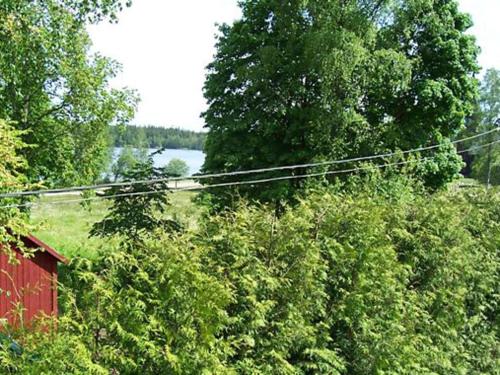 a field with trees and a red building and a body of water at 5 person holiday home in LAMMHULT, SVERIGE in Förhult