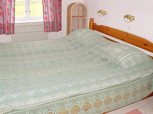 a bed with a green and white blanket on it at 4 person holiday home in GULLSPÅNG-By Traum in Tattertorp