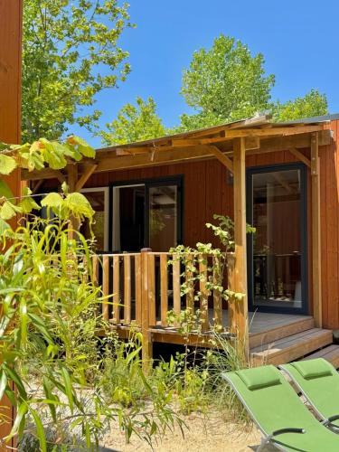 a cabin with a deck and chairs in the yard at Mobil Homes Vacances in Grimaud