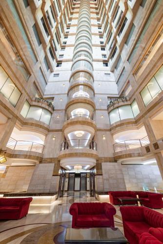 a large lobby with red chairs and a large ceiling at Razana Al Rawdha Hotel in Makkah