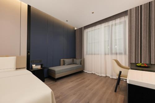 Atour Hotel Shanghai Jing'an North XIzang Road Metro Station في شانغهاي: غرفة نوم بها سرير وأريكة ونافذة