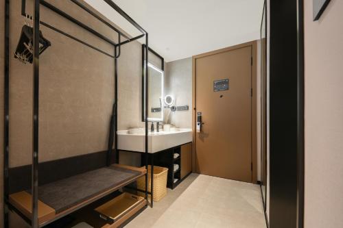 Atour Hotel Shanghai Jing'an North XIzang Road Metro Station في شانغهاي: حمام مع حوض ومرآة