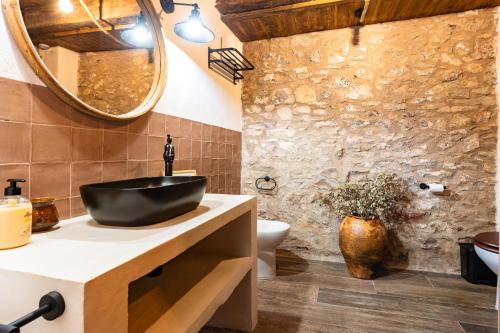 baño con lavabo negro y pared de piedra en Masía La Parreta, en Villafranca del Cid