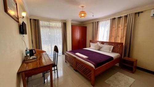 a bedroom with a bed and a desk and a window at Runako Lodge in Arusha