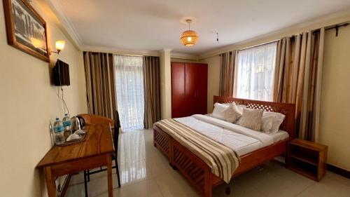 a bedroom with a bed with a desk and a window at Runako Lodge in Arusha