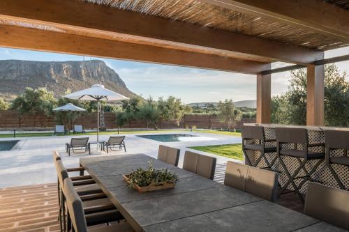 a patio with a table and chairs and a pool at Olive Sun Villa Stillness & Elegance by etouri in Kato Gouves
