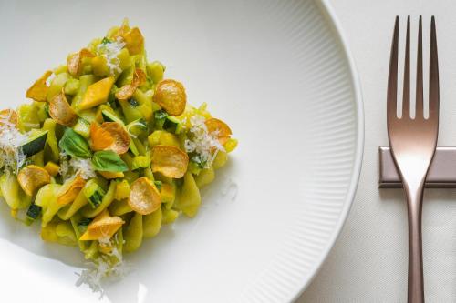a white plate with a salad on a table with a fork at Hotel Nani Mocenigo Palace in Venice