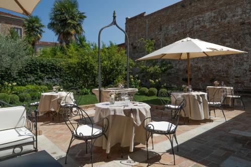 a patio with tables and chairs and an umbrella at Hotel Nani Mocenigo Palace in Venice