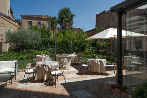 a patio with tables and chairs and an umbrella at Hotel Nani Mocenigo Palace in Venice