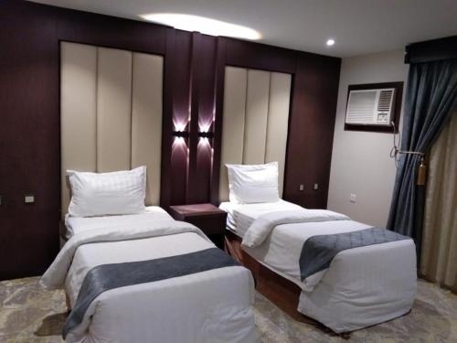 a hotel room with two beds with white sheets at Makarim Palm Hotel in Rabigh