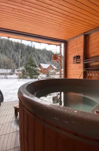 a jacuzzi tub on a deck with a view of the snow at Барнхаус Карпатський подих in Krasnyy