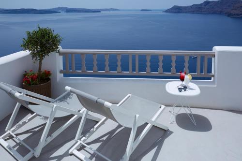 two chairs and a table on a balcony with the ocean at Filotera Suites in Oia