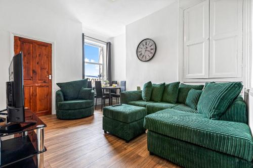 sala de estar con muebles verdes y reloj en la pared en Superking Beds, Smart TVs, Gigabit WiFi, Sleeps 6, en Derby