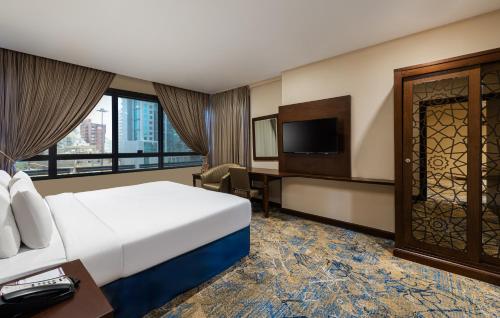 a hotel room with a bed and a desk and a tv at Razana Al Rawdha Hotel in Makkah