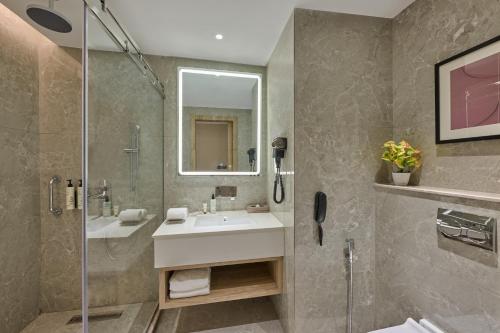 a bathroom with a sink and a shower at Riviera Sarovar Portico Pathankot in Pathānkot