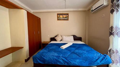 a bedroom with a bed with a blue blanket at Runako Lodge in Arusha