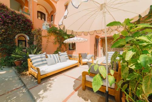 - une terrasse avec 2 canapés et un parasol dans l'établissement Villa Chiara - Lavi Luxury Apartments, à Capri
