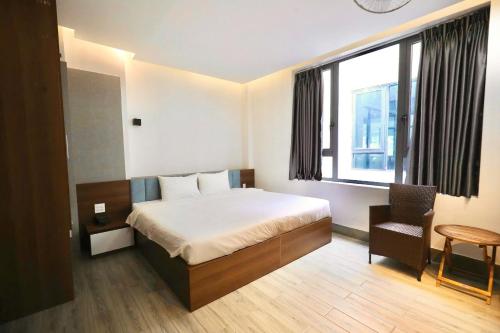 a bedroom with a bed and a chair and a window at HAKU Boutique Hotel Tuy Hoà - APEC Mandala in Tuy Hoa