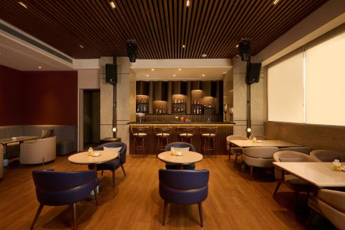 a restaurant with tables and chairs and a bar at Riviera Sarovar Portico Pathankot in Pathānkot