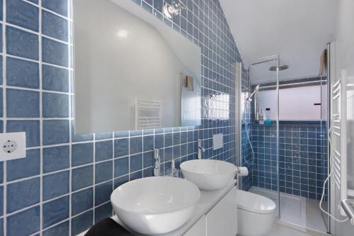 a blue tiled bathroom with a toilet and a sink at Flor de Sá in Aveiro