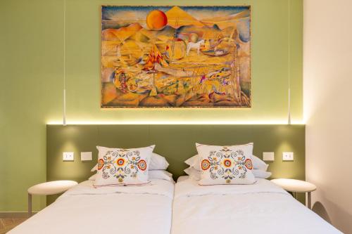 two beds in a room with a painting on the wall at Albergo Ristorante Corsini in Pavullo nel Frignano