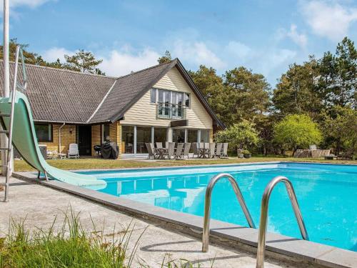 a swimming pool with a slide in front of a house at 14 person holiday home in Sjællands Odde in Tjørneholm