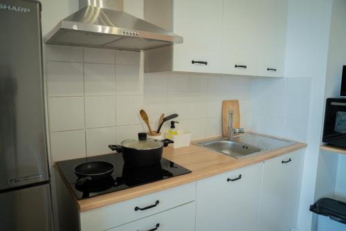 a kitchen with a stove with two pots and a sink at Bel appartement vue mer - Mafat'appart in La Possession