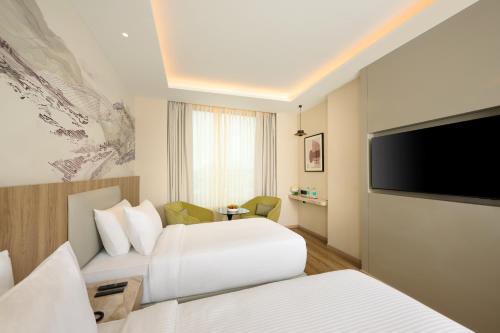 a hotel room with two beds and a flat screen tv at Riviera Sarovar Portico Pathankot in Pathānkot
